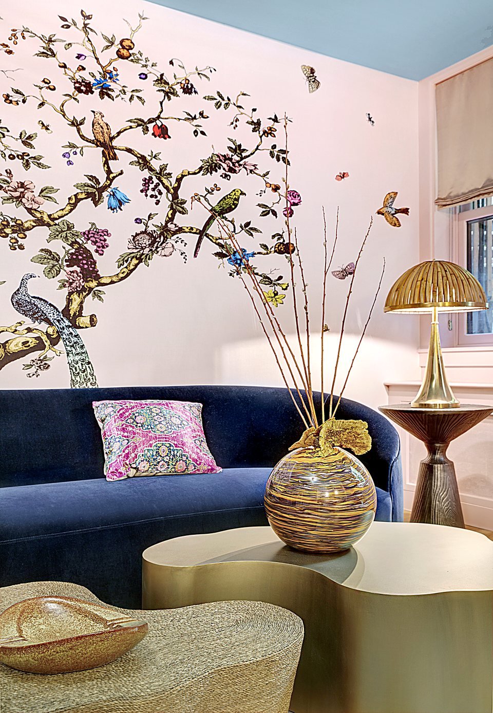 Round sunburst mirror and sculptural ceramics styled beside a brass table lamp